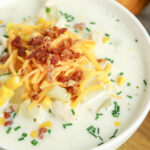 Crockpot Chicken Corn Chowder in white bowl topped with shredded cheese and bacon bits