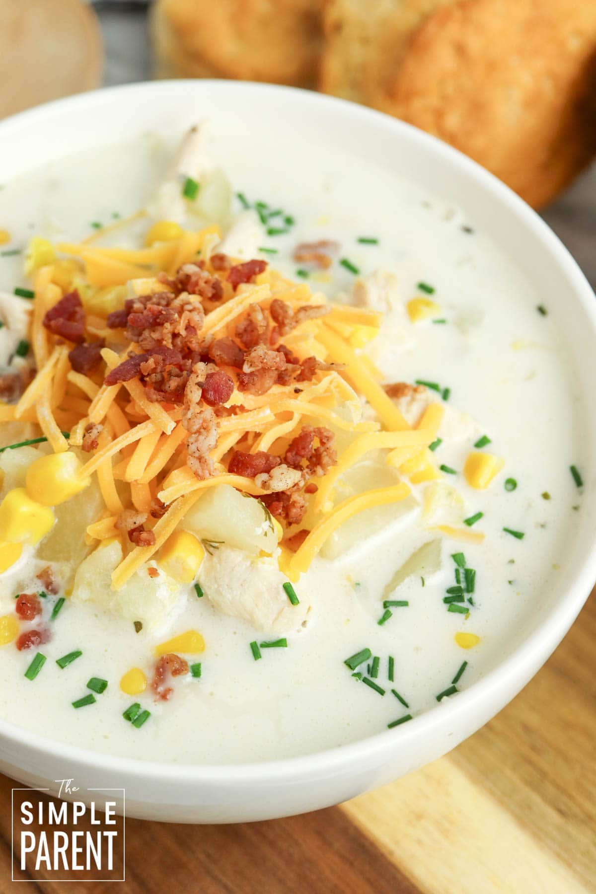 Crockpot Chicken Corn Chowder in white bowl topped with shredded cheese and bacon bits
