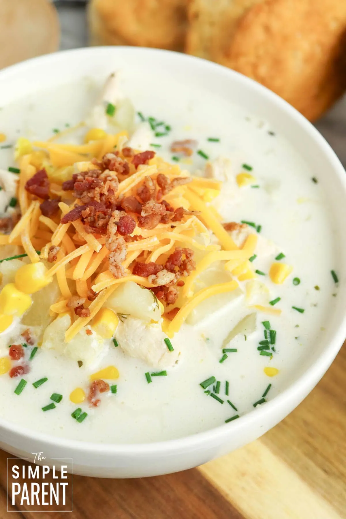 Crockpot Chicken Corn Chowder in white bowl topped with shredded cheese and bacon bits