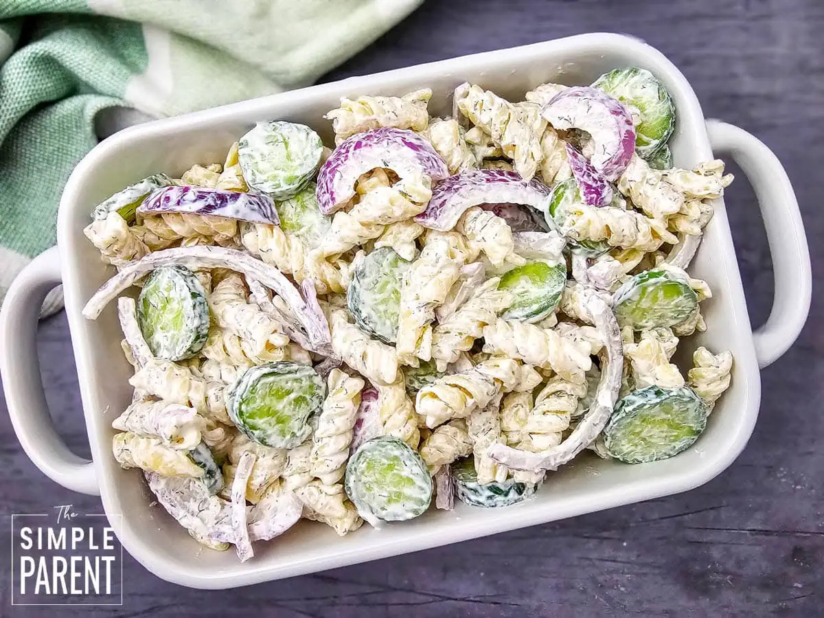 dill cucumber pasta salad in white serving dish on dark counter