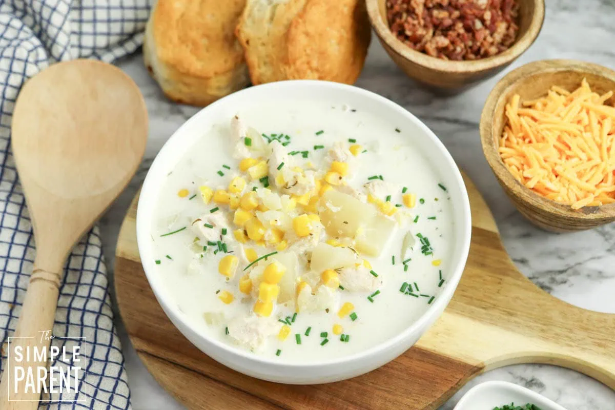 Chicken corn chowder in white bowl on wooden cutting board