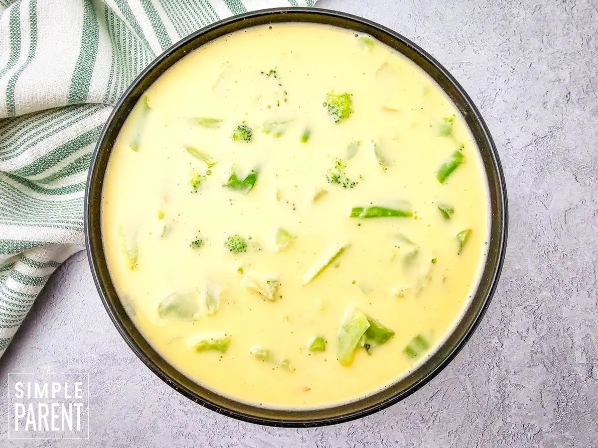 Creamy broccoli cheese soup in black bowl on gray counter