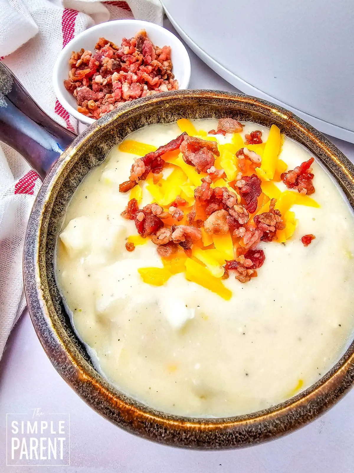 Bowl of Crockpot Loaded Baked Potato Soup topped with bacon bits and shredded cheddar cheese