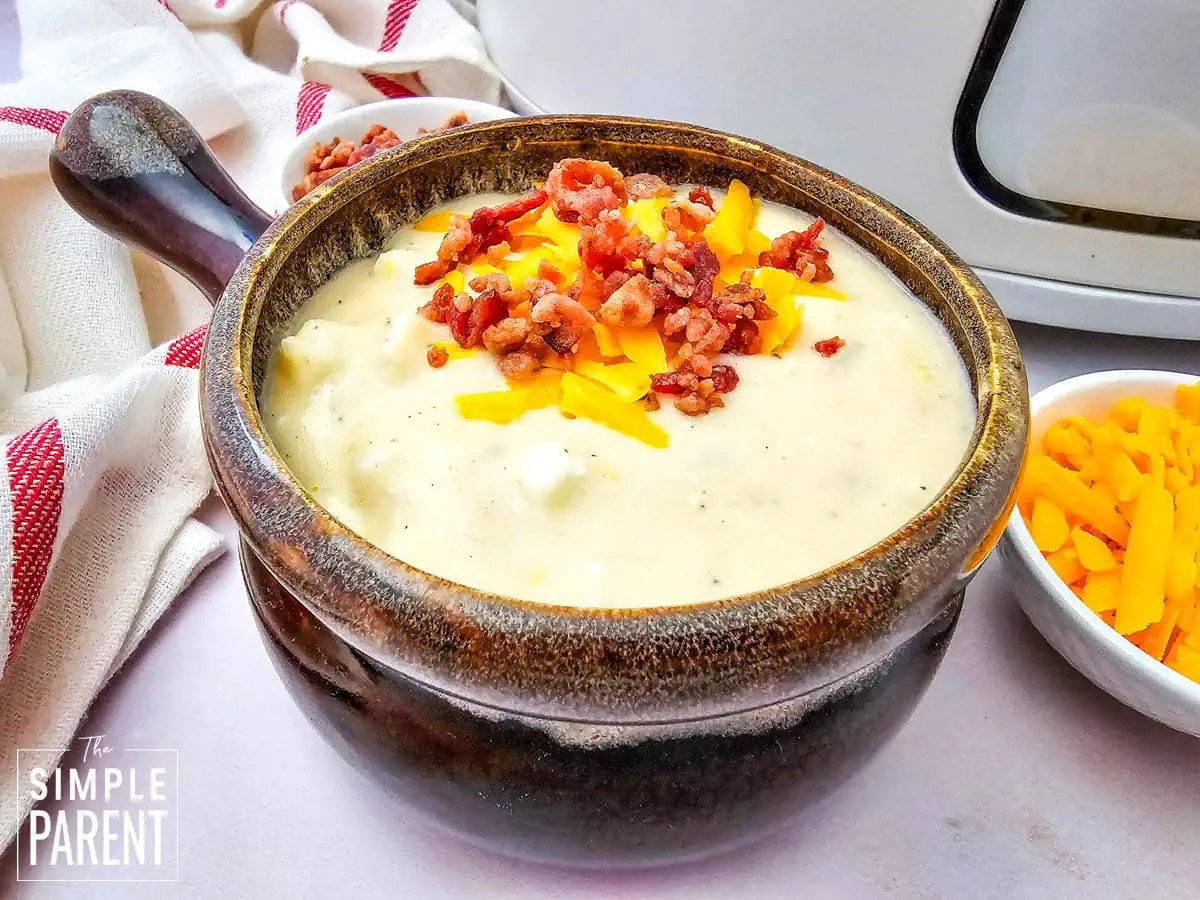 Crockpot Loaded Baked Potato soup in brown soup bowl topped with bacon bits and cheese