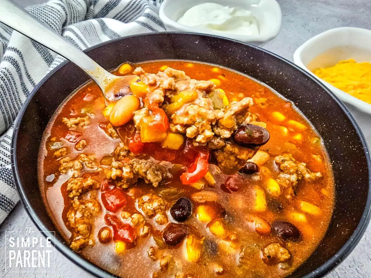 Spoonful of Taco soup with ground beef in black bowl